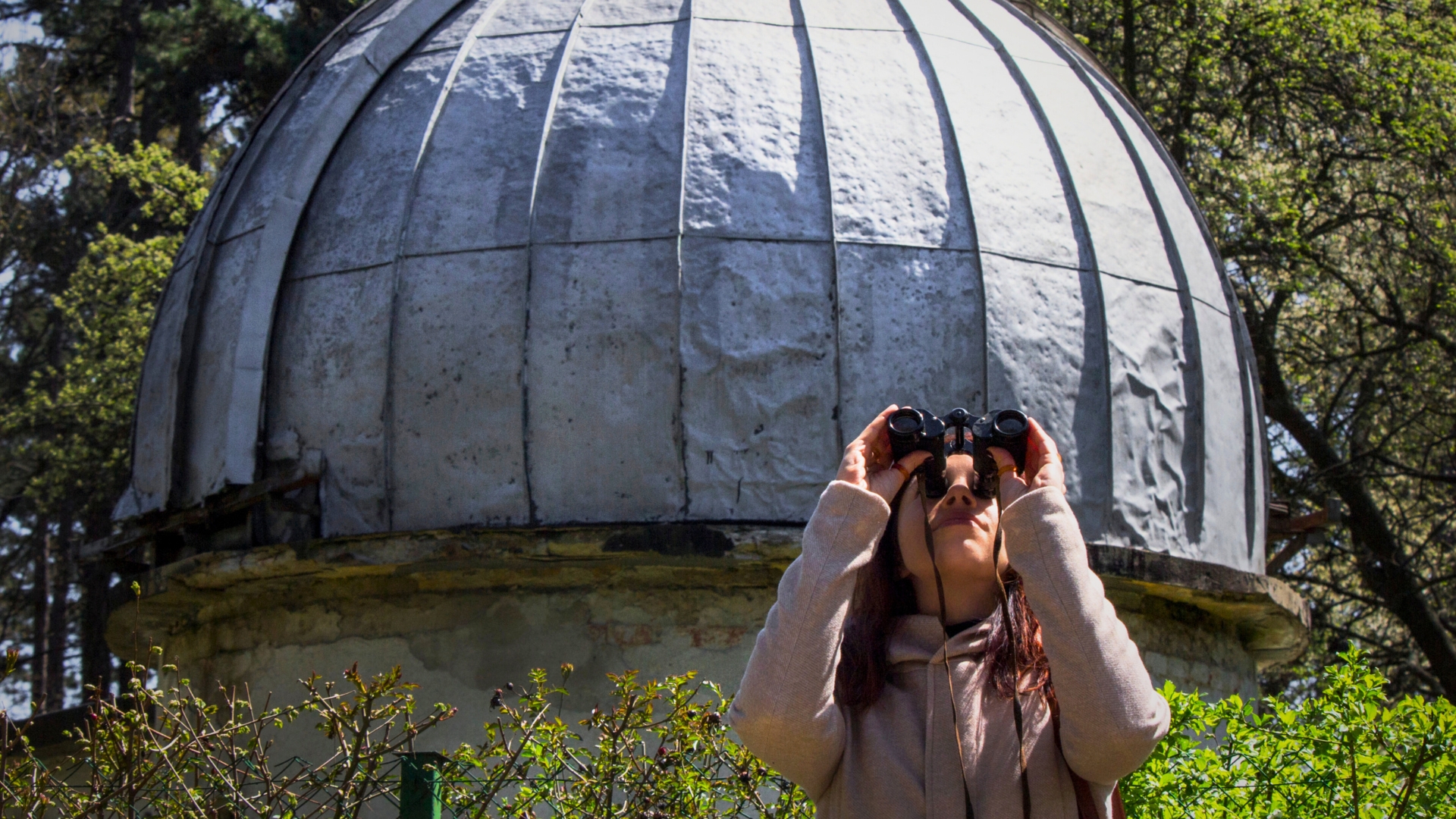 Una mujer joven mira a traves de binoculares