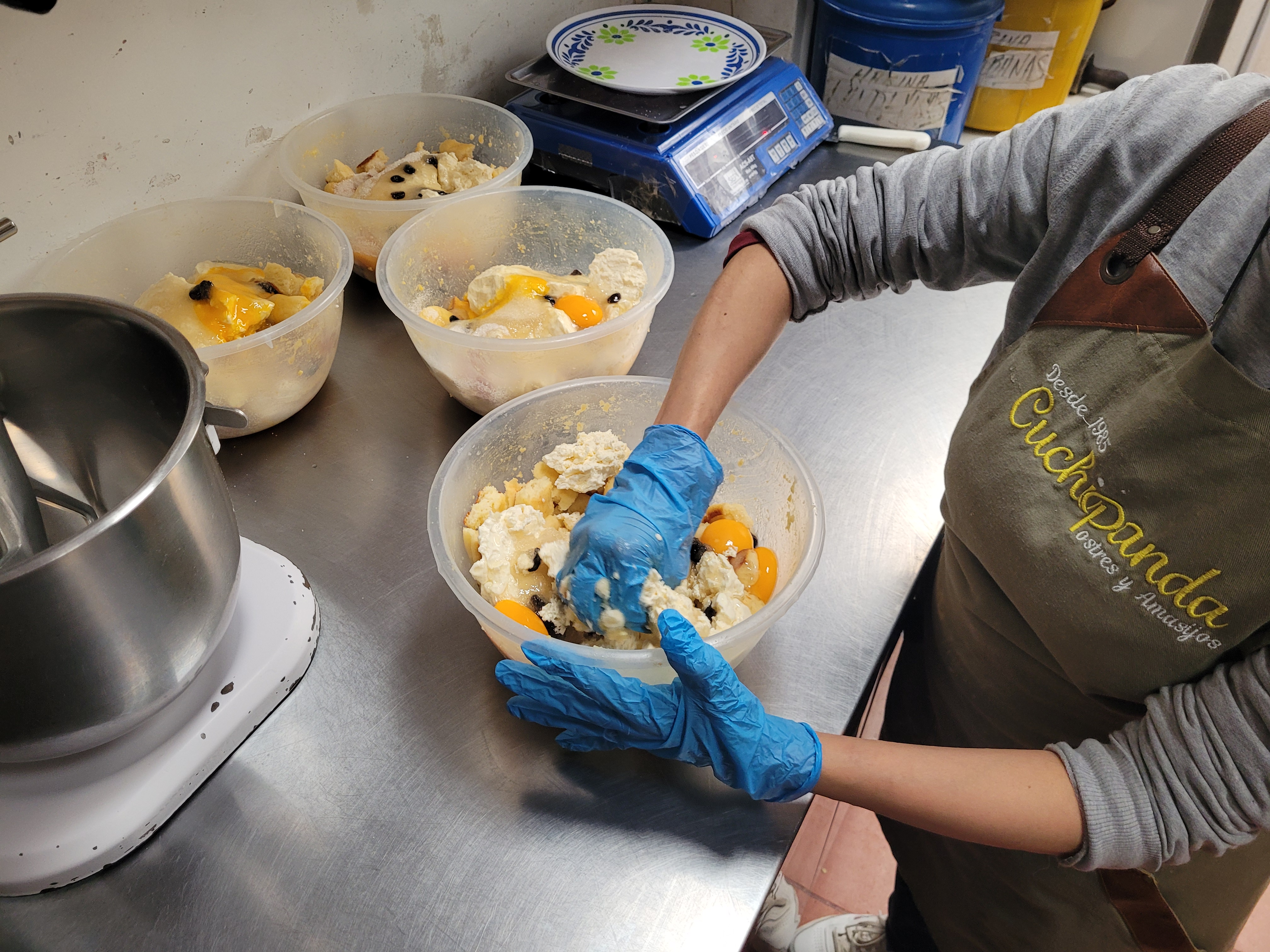 Una mujer con delantal verde está mezclando ingredientes para formar la torta de almojábana, plato estrella de Cuchipanda.