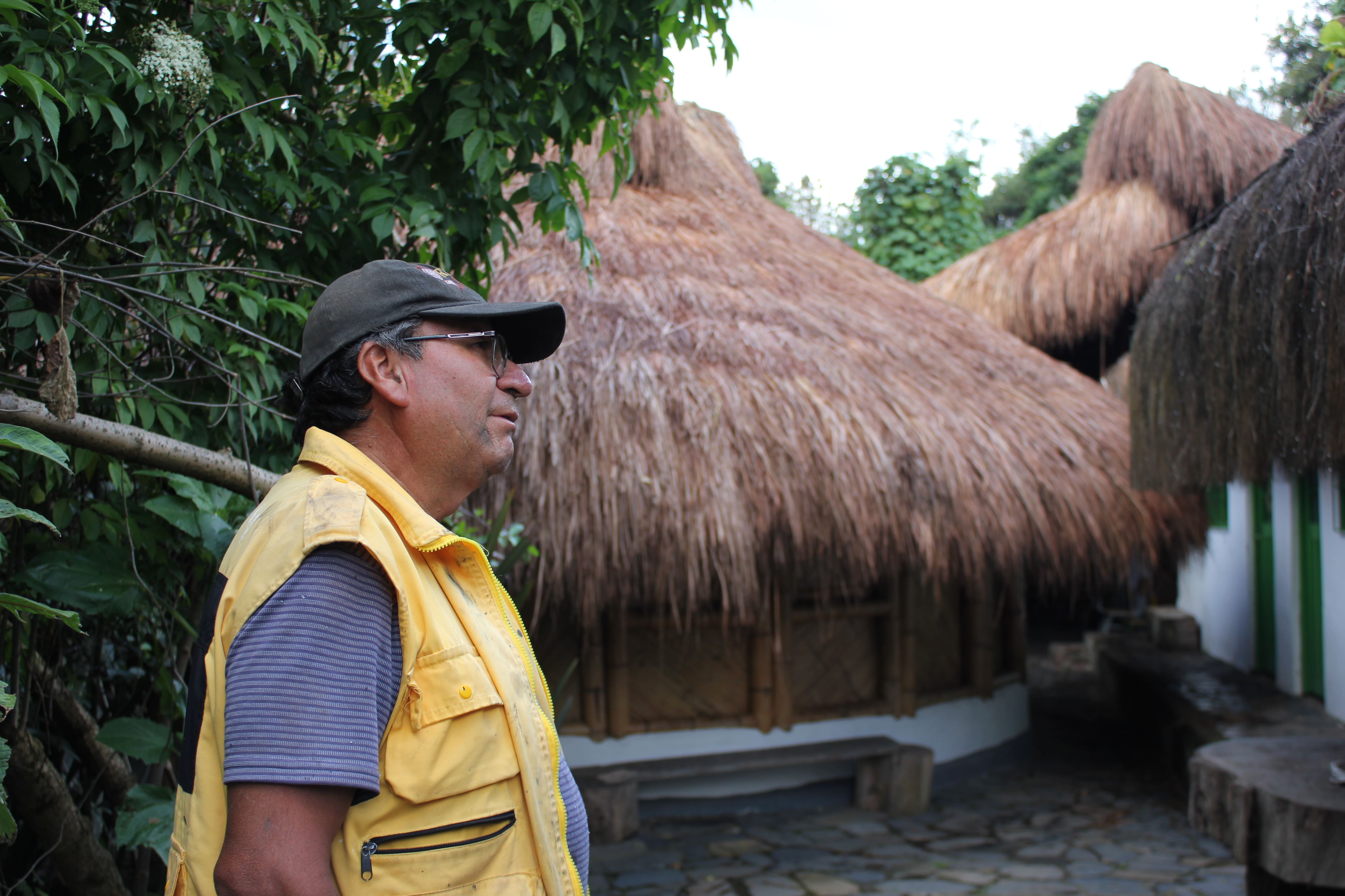 Pablo Tauta, un indigena del resguardo de Cota, situado en los templos importantes de su comunidad. Está de perfil con una gorra gris, un chaleco amarillo. 