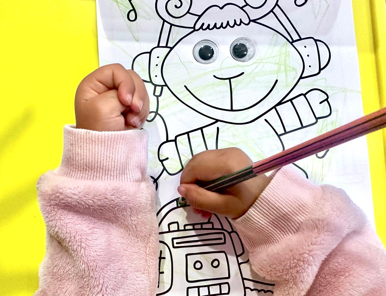 Manos de una niña de 4 años coloreando su dibujo. 