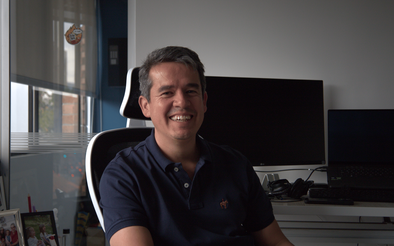 Eivar Rojas Castro en su oficina, sonriendo en medio de la jornada de trabajo.