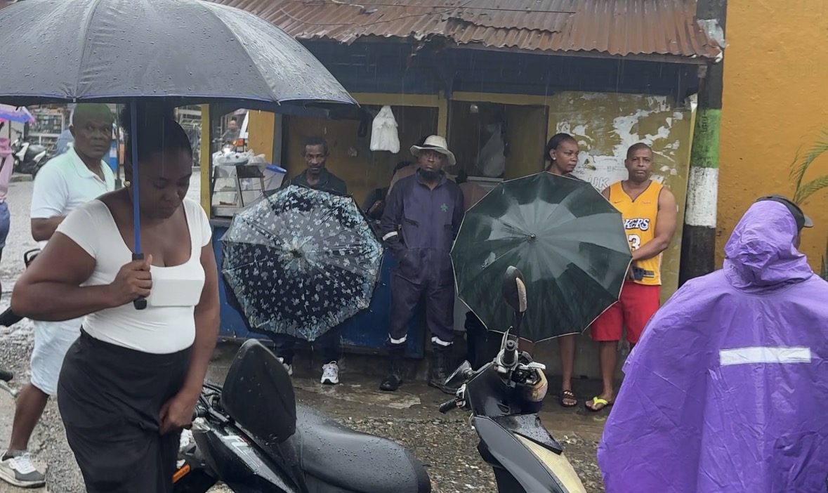 Personas resguardandose de la lluvia fuera de un puesto de votación en el Chocó