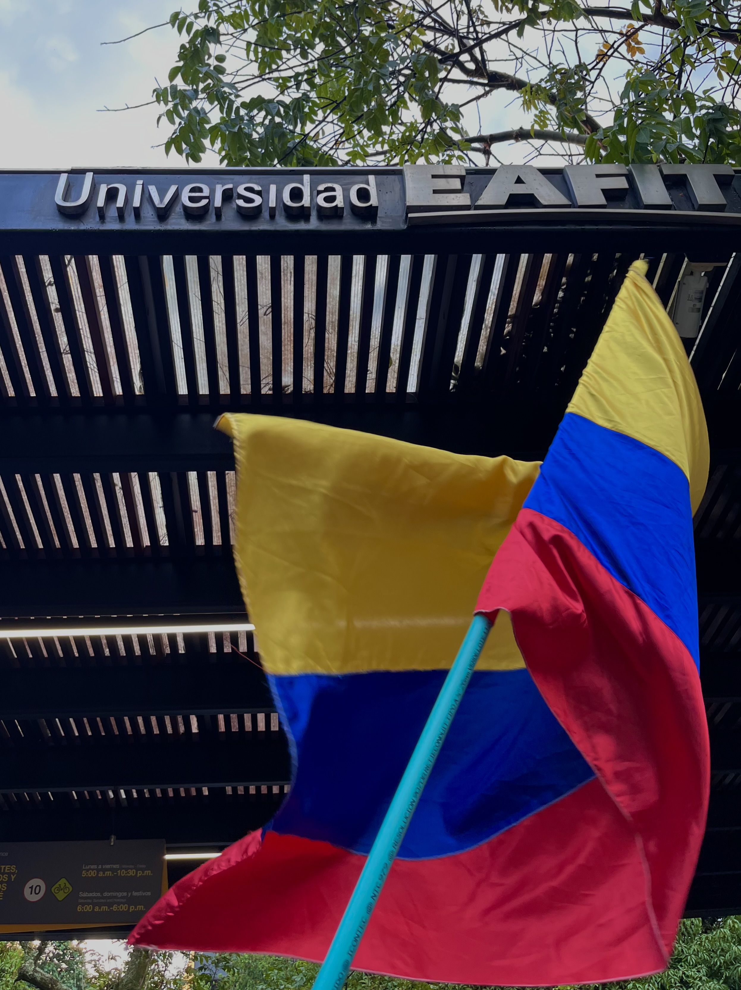 Una bandera de Colombia ondeando frente a la entrada principal de la Universidad EAFIT