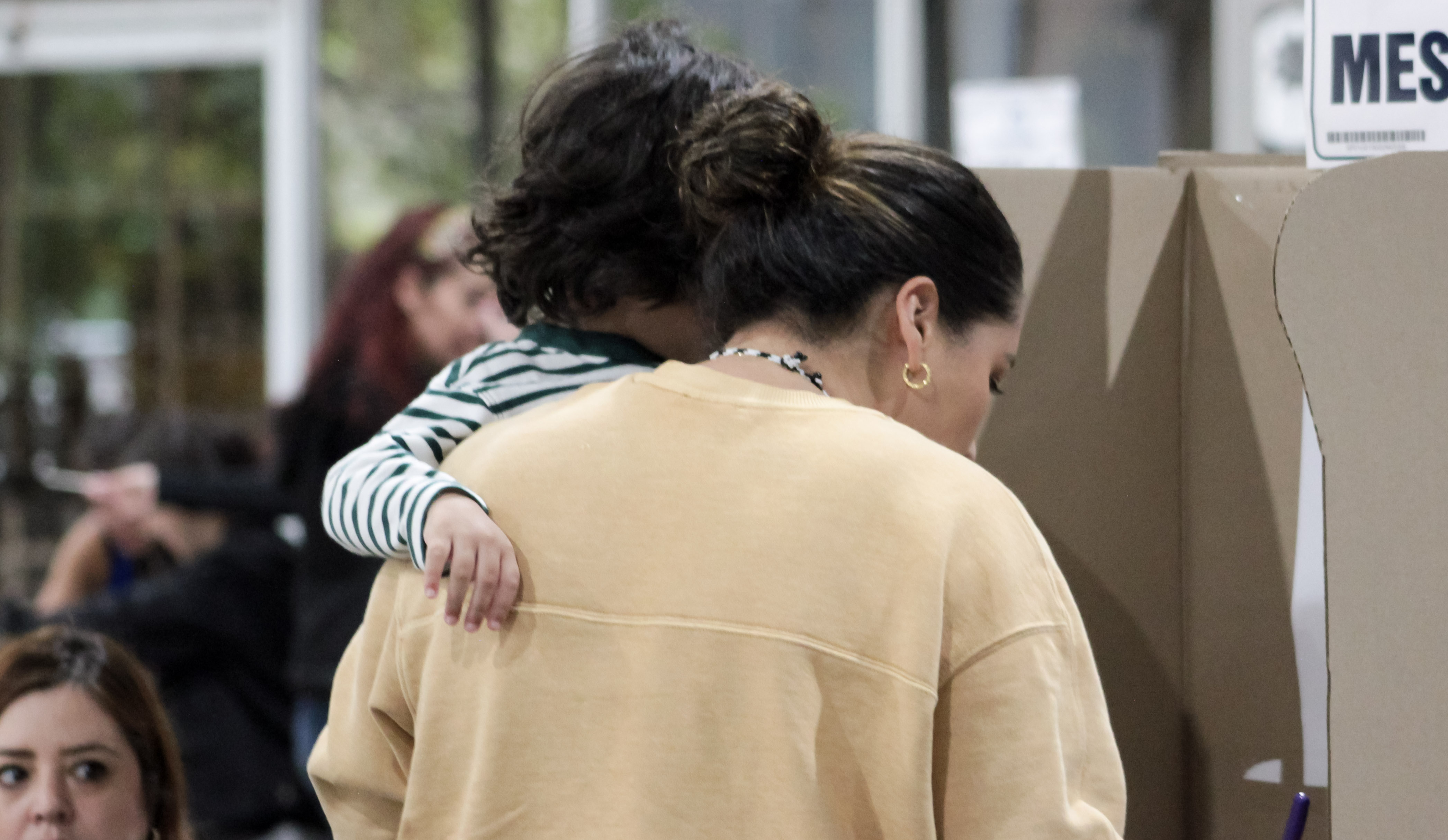 Madre ejerciendo su derecho al voto con su hijo en brazos