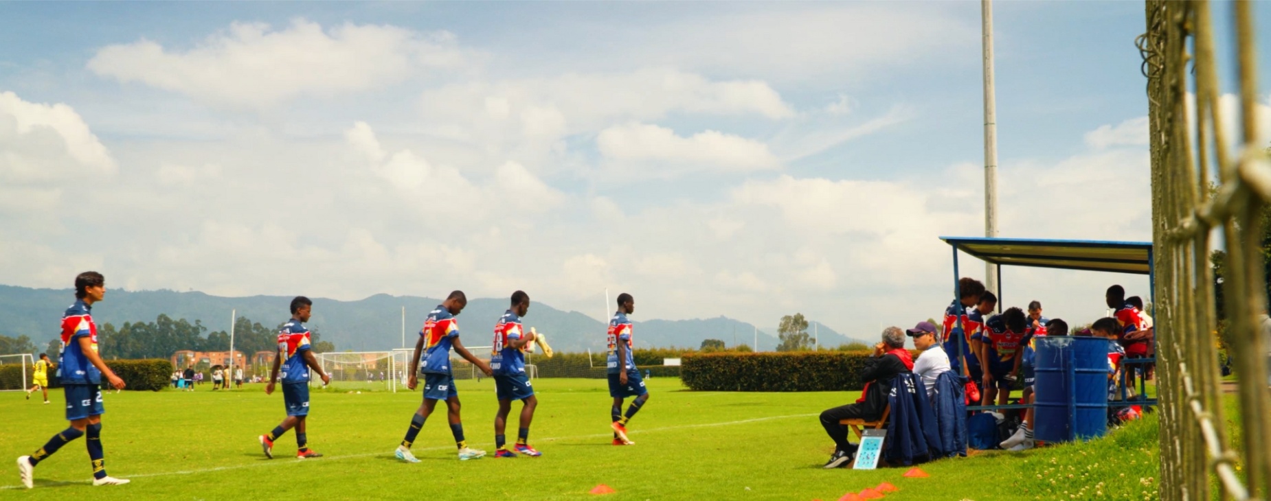 En la banca los futbolistas esperan, como miles de jóvenes en el país, su turno para entrar al juego.