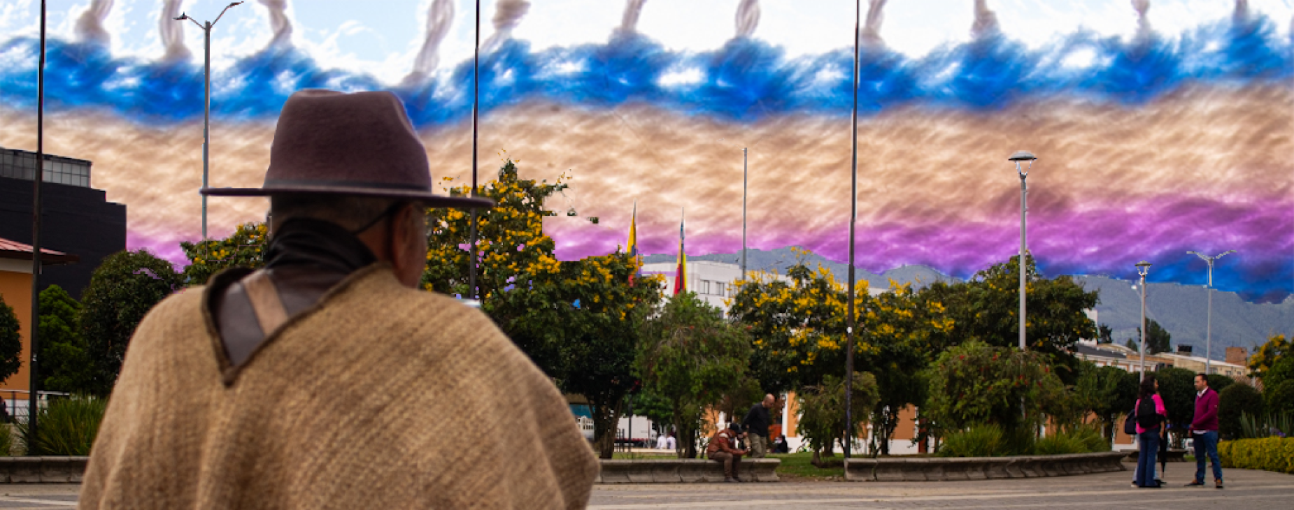 Un hombre con una ruana y sombrero típico observa la ciudad de Cajicá. En el cielo se ve el borde de un tapiz colorido.